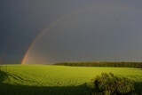 Rainbow in a green field against a dark stormy sky