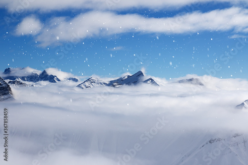 High snowy mountains covered with beautiful sunlight clouds in snowfall