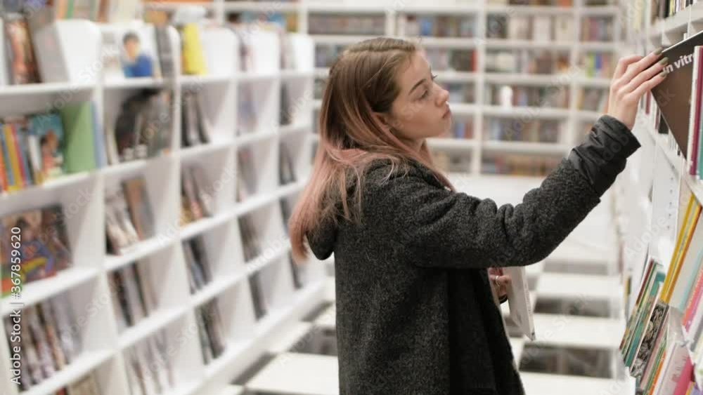 portrait attractive young pink-haired woman choosing book in bookstore portrait attractive young pink-haired woman choosing book in bookstore