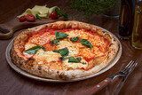 High Angle View of Fresh Baked Margherita Pizza Topped with Tomatoes, Cheese and Fresh Basil on Wooden table
