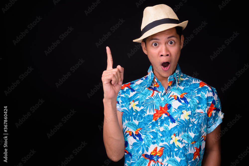 Young Asian tourist man ready for vacation against black background Young Asian tourist man ready for vacation against black background