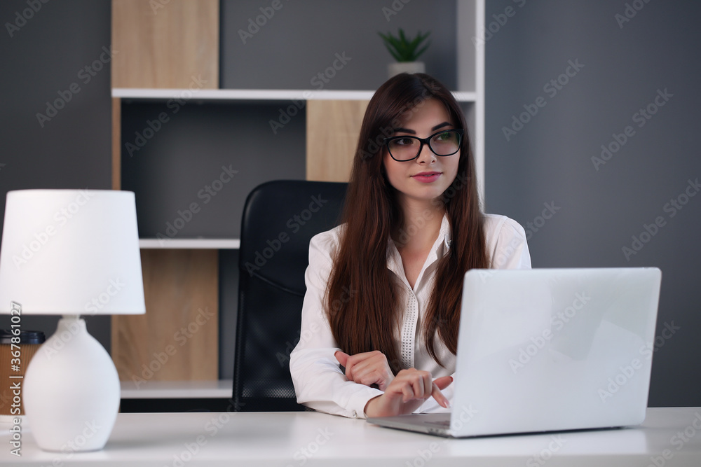 Young pretty brunette business woman with laptop in the office Young pretty brunette business woman with laptop in the office