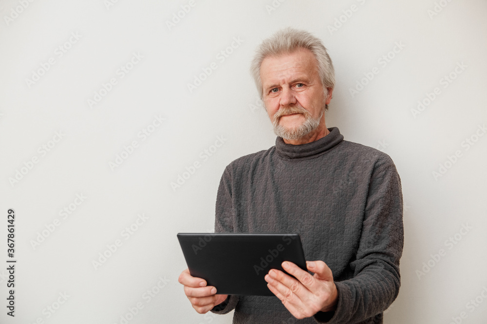 Elderly man holding a tablet computer on a white background in studio