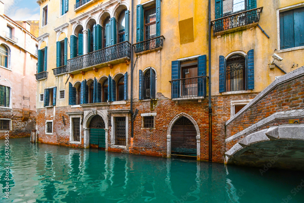 A typical, picturesque and colorful residential canal at high water in the historic center of Venice, Italy with emerald green water.