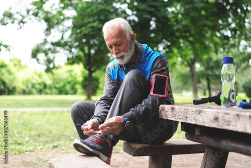 Senior man tying shoelace getting ready for workout at park