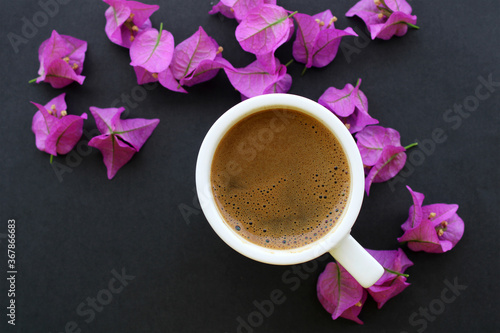 cup of coffee with pink flowers, black background