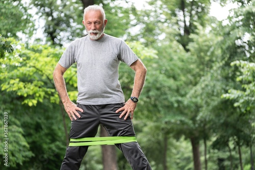 Senior sportsman exercising for glutes using resistance band at park