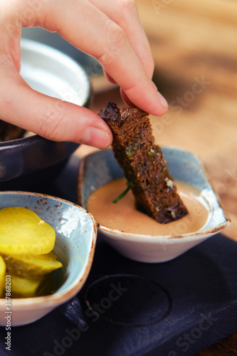 A woman's hand dips a piece of black bread into the sauce
