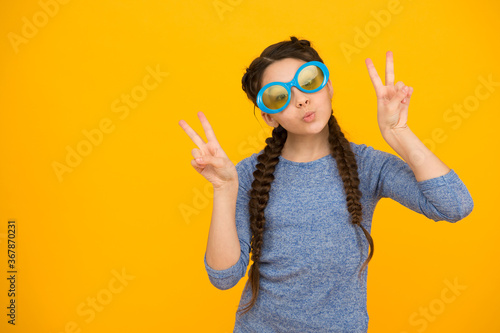 showing piece gesture. kid fashion and beauty. small girl looking cool. childhood happiness. beautiful braided long hair. stylish braids and pigtails. party fun. funny teenage girl in glasses