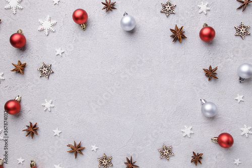 Winter holiday vibes. Frame made of festive decorations, baubles and snowflakes on grey stone surface. Seasonal background, Christmas, New Year composition. Flat lay, copy space