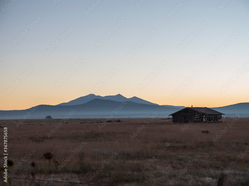 An historic cabin on a vast prairie with distant mountains