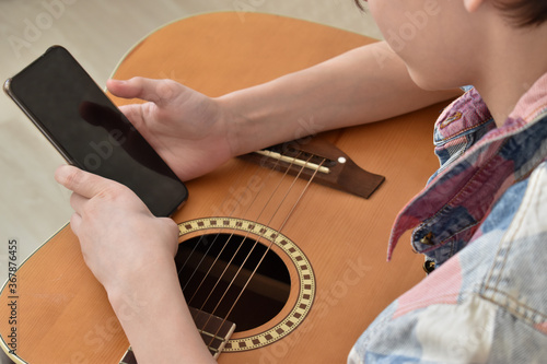 Child's hands hold the guitar and phone