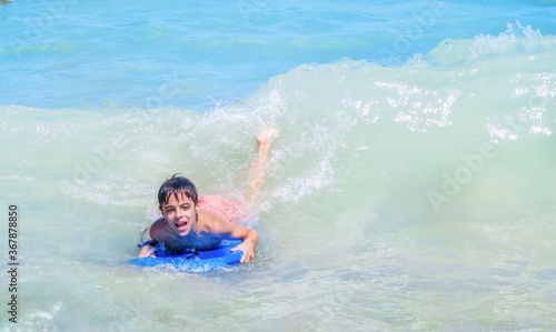 child bodyboarding a wave in a blue sea with an expression of fun and happiness on his face   © Javier