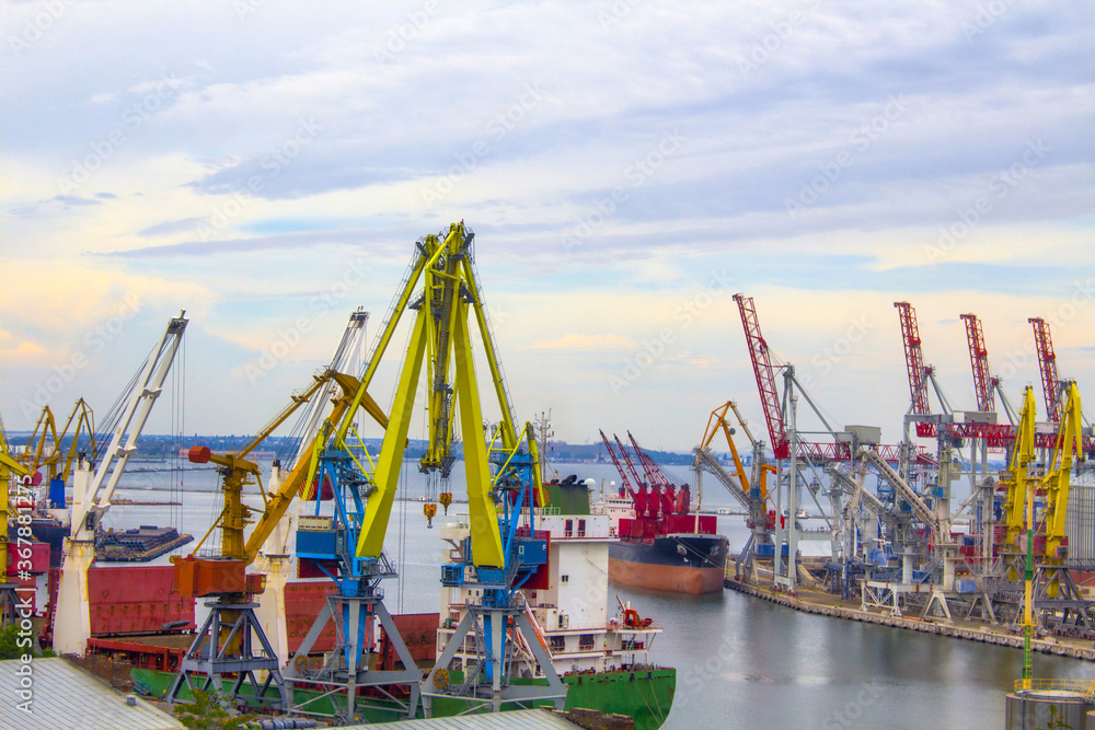 panorama port container loading, transportation. portal cranes in the evening port in Odessa, Black Sea. a heavy lift vessel docked at sea. in the background are residential and commercial buildings