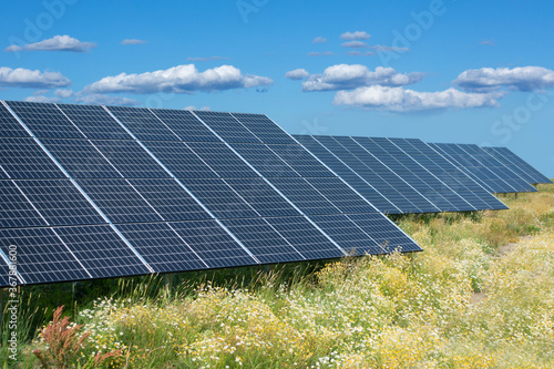 Energy park with solar panels in green meadow on blue sky