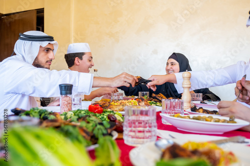 Happy arabic muslim family eating together in a family meeting for iftar in ramadan