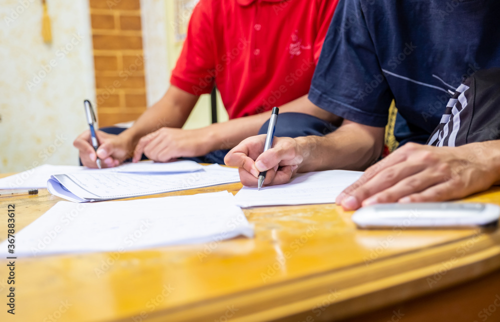 Two boys sitting together studying and writing their homework Two boys sitting together studying and writing their homework