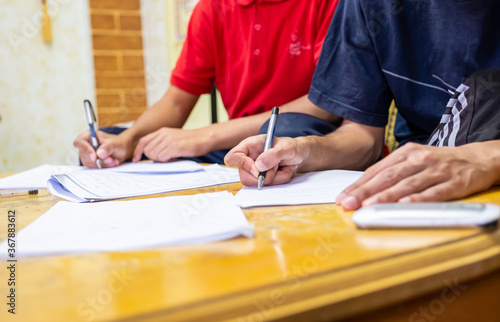 Two boys sitting together studying and writing their homework