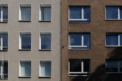 Outdoor sunny exterior front view, typical facade of modern residence or apartment in city of Europe with rectangular windows and earth tone wall.