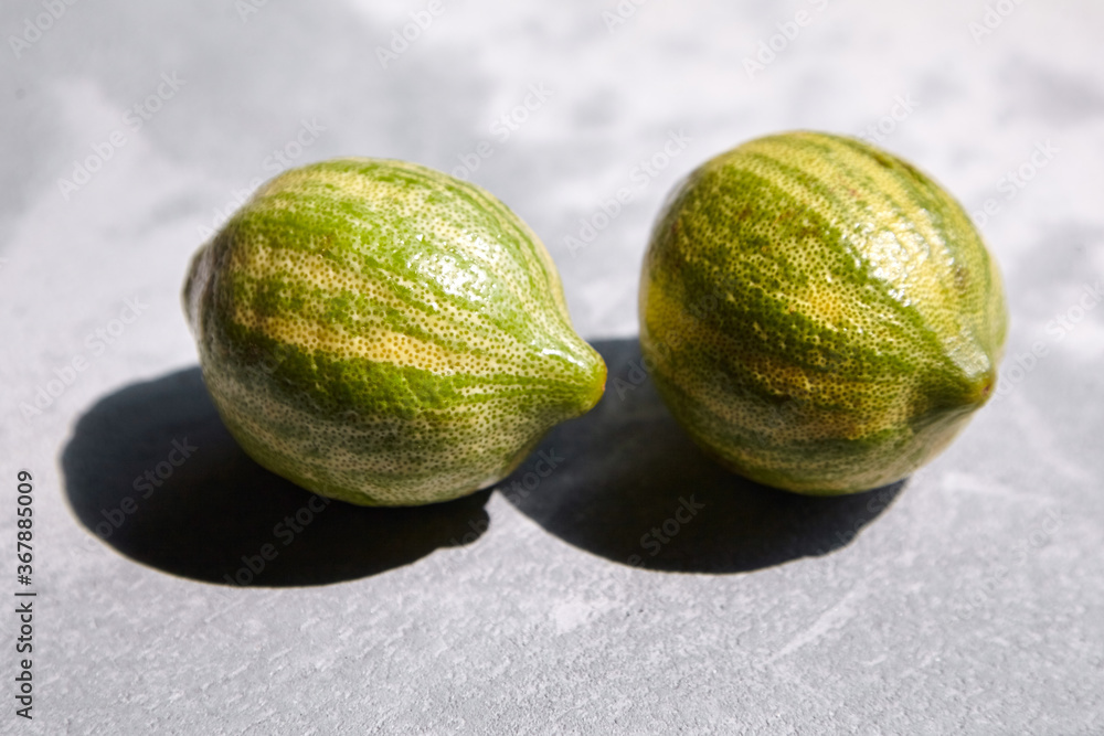 Variegated pink lemons or pink-fleshed Eureka lemons on gray concrete table. Whole citrus fruits with striped rind Variegated pink lemons or pink-fleshed Eureka lemons on gray concrete table. Whole citrus fruits with striped rind