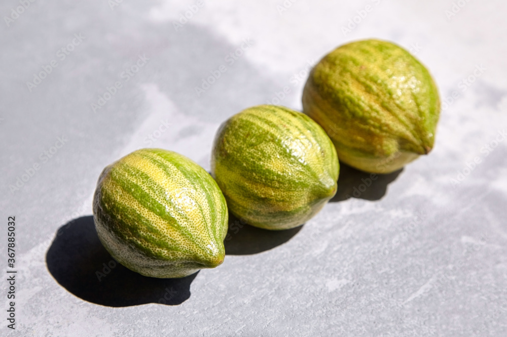 Variegated pink lemons or pink-fleshed Eureka lemons on gray concrete table. Whole citrus fruits with striped rind Variegated pink lemons or pink-fleshed Eureka lemons on gray concrete table. Whole citrus fruits with striped rind