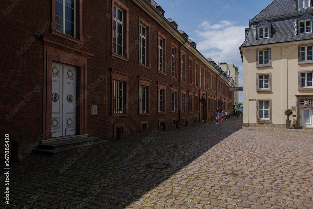 Outdoor sunny street view with walking peoples at narrow alley in front of Stadtmuseum Düsseldorf, Germany.