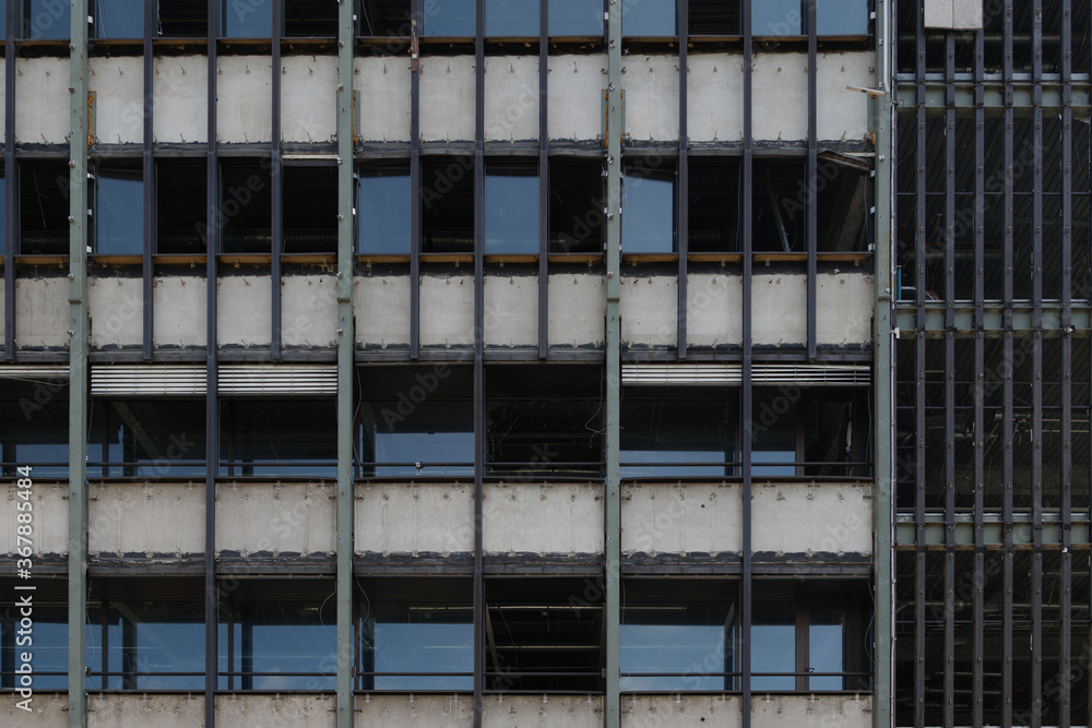 Front view of remaining typical modern facade of office Building demolition. Demolished construction site in the city. Front view of remaining typical modern facade of office Building demolition. Demolished construction site in the city.