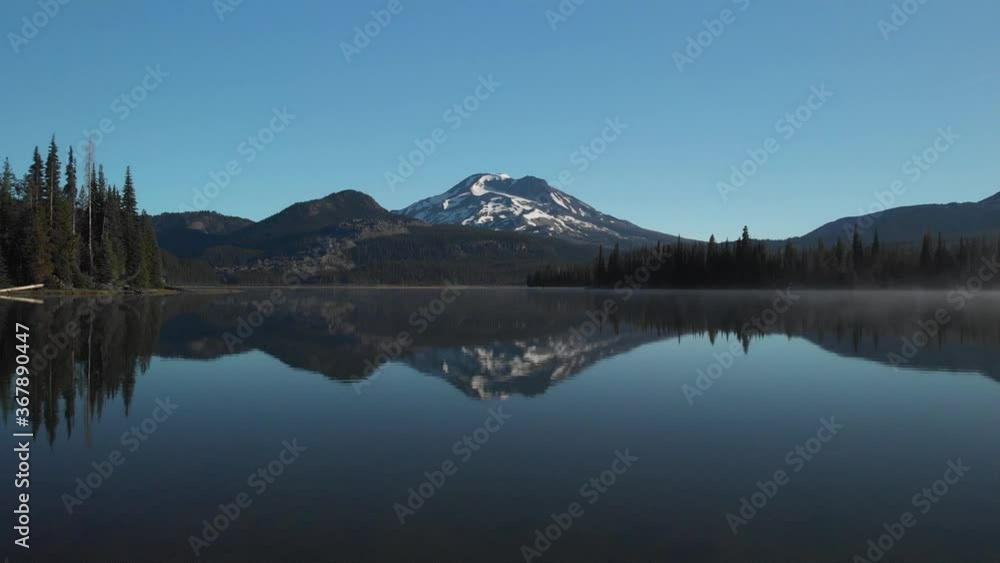 Aerial drone flight over log amazing reflection water lake mountain broken top south sisters cascade forest tree range blue sky mist beautiful sparks lake central bend oregon pacific northwest usa Aerial drone flight over log amazing reflection water lake mountain broken top south sisters cascade forest tree range blue sky mist beautiful sparks lake central bend oregon pacific northwest usa
