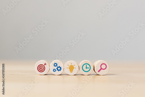 Conceptual of business strategy and action plan. Wooden sphere with icon aim, cog, lamp, time and magnifying glass on wood table