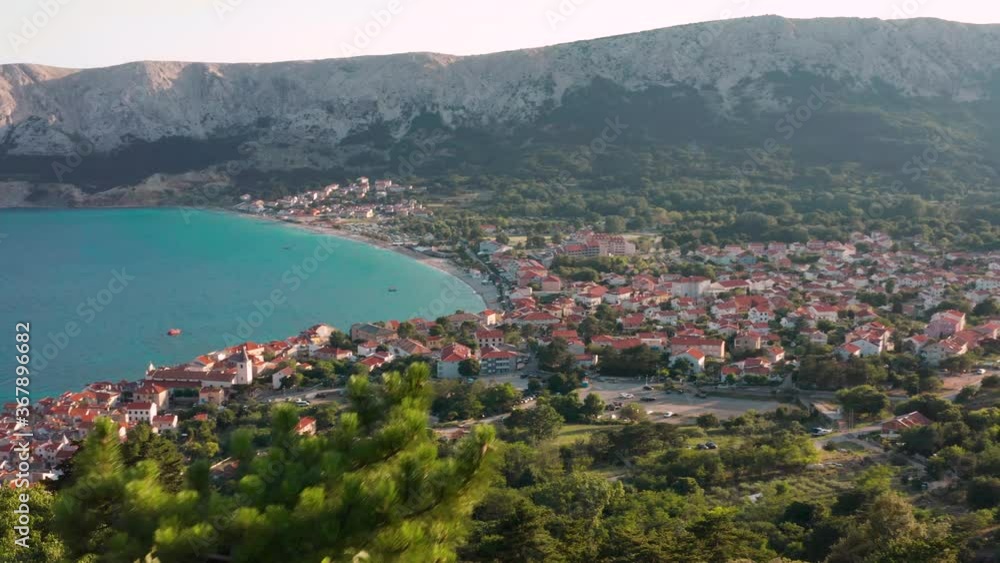 The Lush Green Trees By The Mountains Overlooking The Scenic Town of Baska And The Calm Bue Sea In Krk, Island, Croatia. - aerial drone The Lush Green Trees By The Mountains Overlooking The Scenic Town of Baska And The Calm Bue Sea In Krk, Island, Croatia. - aerial drone