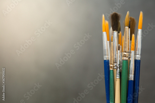 Many art brushes on a cement background with warm light and copy space