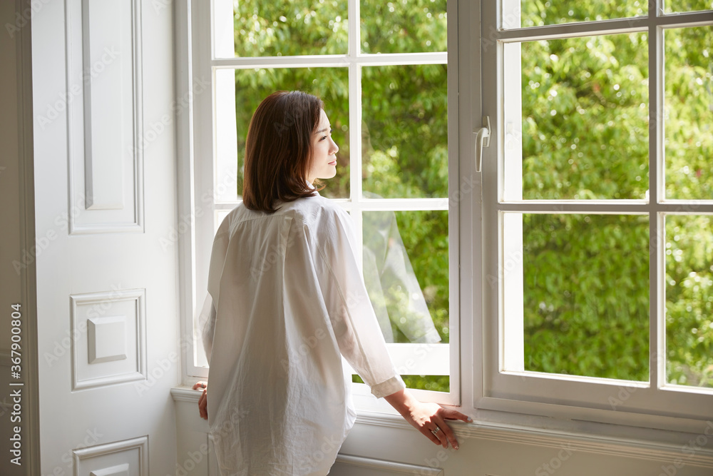 young asian woman staying at home looking out of winow young asian woman staying at home looking out of winow