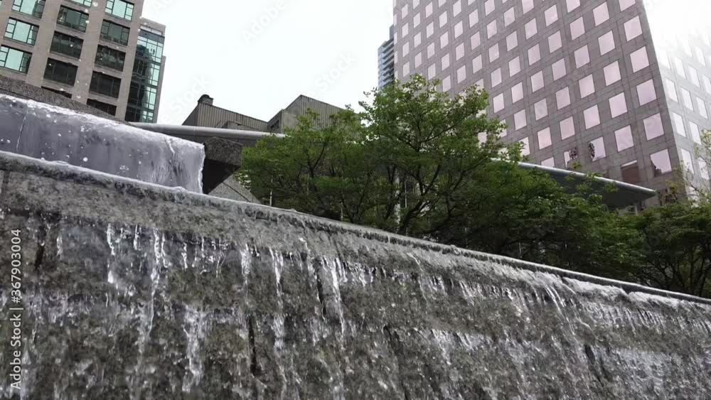 Angled view of marble waterfalls with luxury skyscrapers surrounding it on a cloudy day in the city dire quietness and calm. Angled view of marble waterfalls with luxury skyscrapers surrounding it on a cloudy day in the city dire quietness and calm.