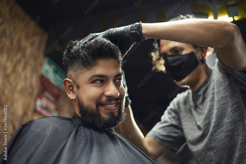 smiling bearded man getting a haircut from a hairdresser