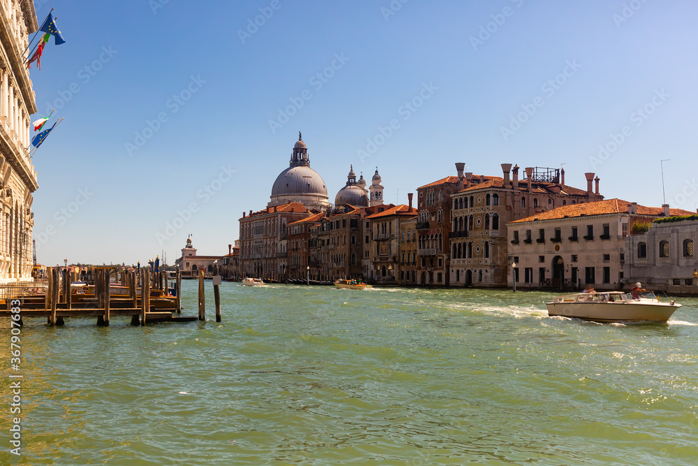 Scenic view of Grand Canal with old colorful architecture of central districts and Baroque domes of Santa Maria della Salute in sunny day, Venice, Italy