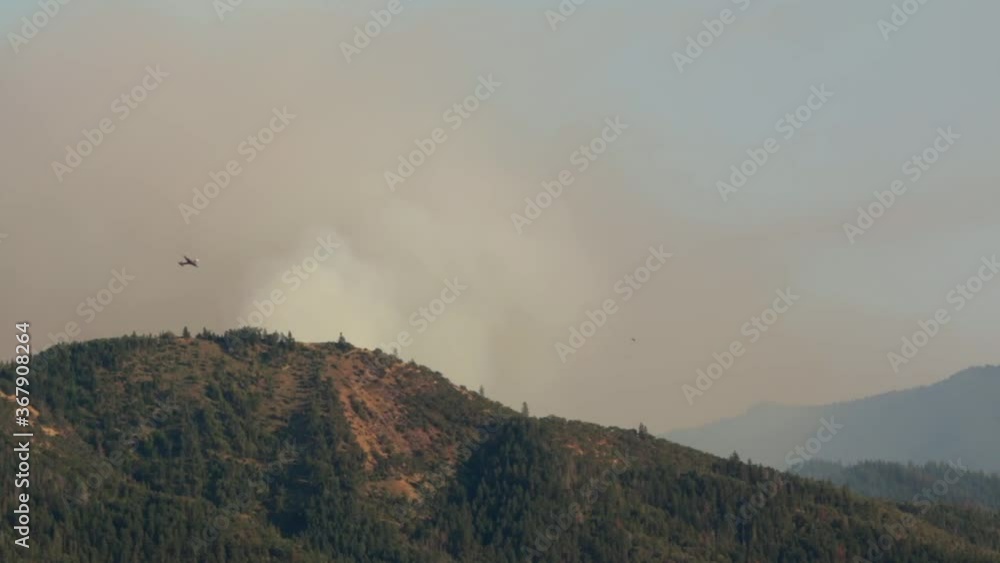 Smoke jumper plane flies by massive wildfire in the mountains Smoke jumper plane flies by massive wildfire in the mountains