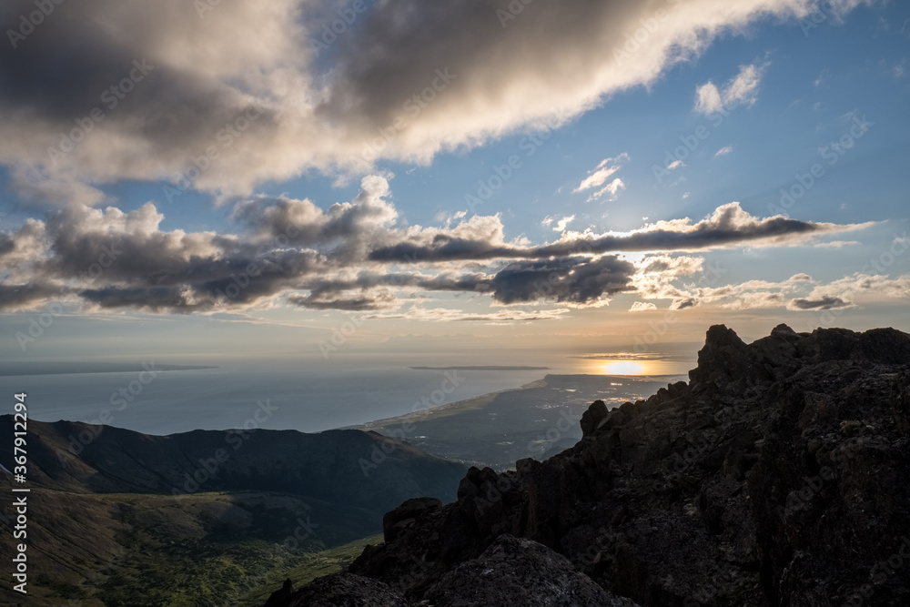 Obraz premium The expanse of the sea is in stark contrast with the coarse landscape of the Chugach Mountains