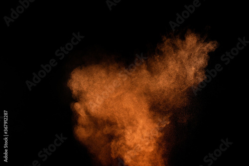 Orange powder explosion on black background. Colored powder cloud. Colorful dust explode. Paint Holi.