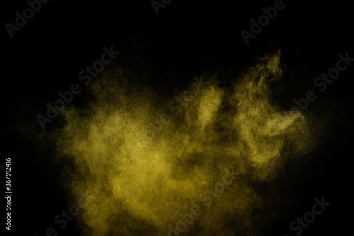 Yellow powder explosion on black background. Colored powder cloud. Colorful dust explode. Paint Holi.