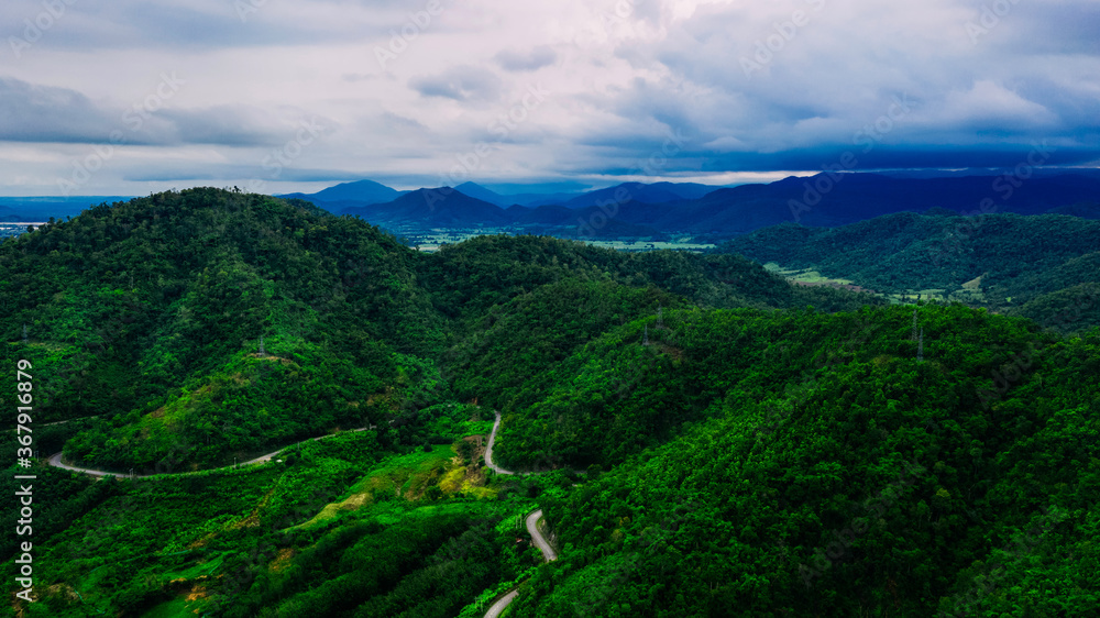 Aerial view or drone shot of road thru mountains with green forest in Asia.