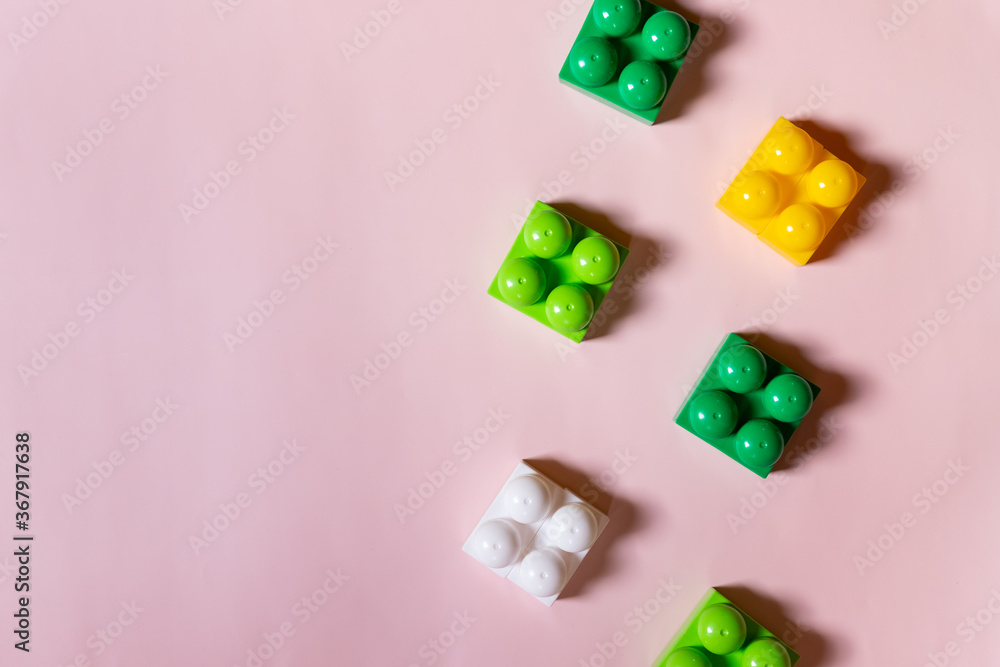 Obraz premium Toys blocks frame,vivid plastic building bricks, group of colorful game pieces.Colorful baby toys on pink background. developing blocks. Creative, logical thinking concept. Flat lay. Copy space.