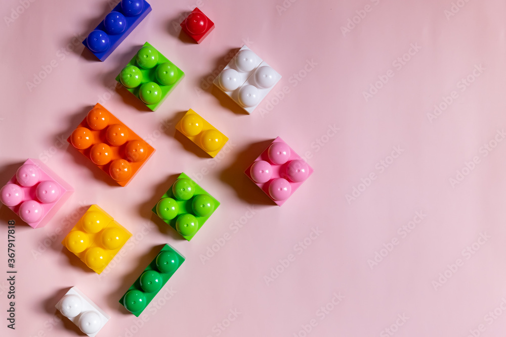 Toys blocks frame,vivid plastic building bricks, group of colorful game pieces.Colorful baby toys on pink background. developing blocks. Creative, logical thinking concept. Flat lay. Copy space.