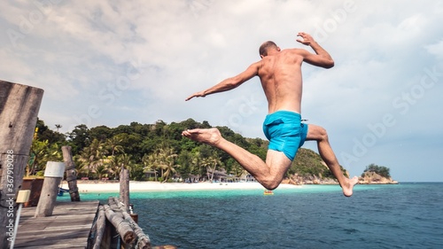 Man jumping from a deck in a paradise island. 