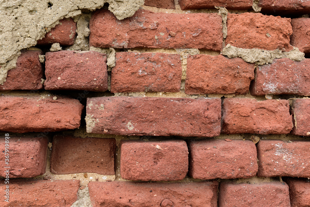 Fototapeta premium Ancient brick wall for a backdrop. Concrete, plaster. Red color. Dispersal, destruction, weathering.