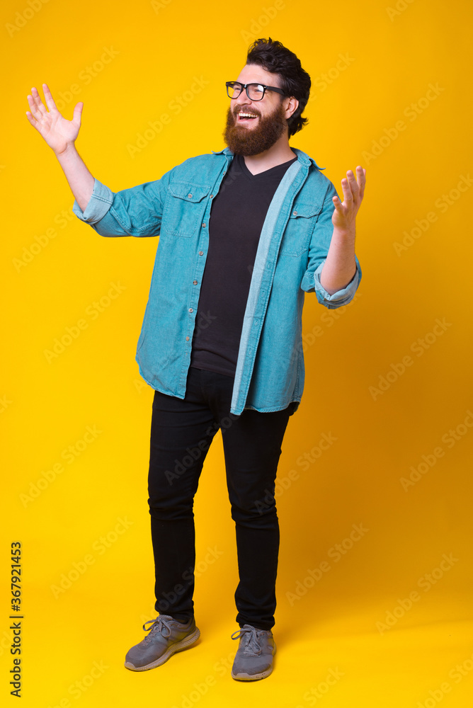 Full length photo of cheerful smiling young man making welcome gesture.