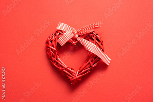 Red heart shape toy with a ribbon on the red background.