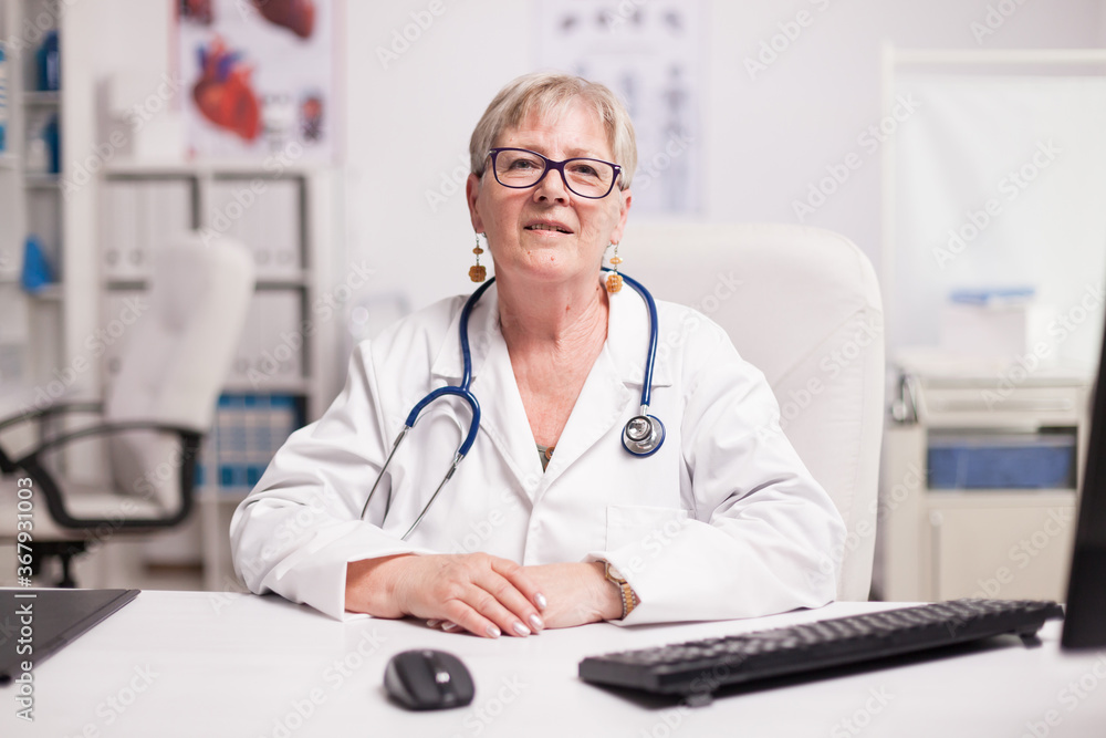 Senior medical practitioner with stethoscope in hospital cabinet smiling to camera. Senior medical practitioner with stethoscope in hospital cabinet smiling to camera.