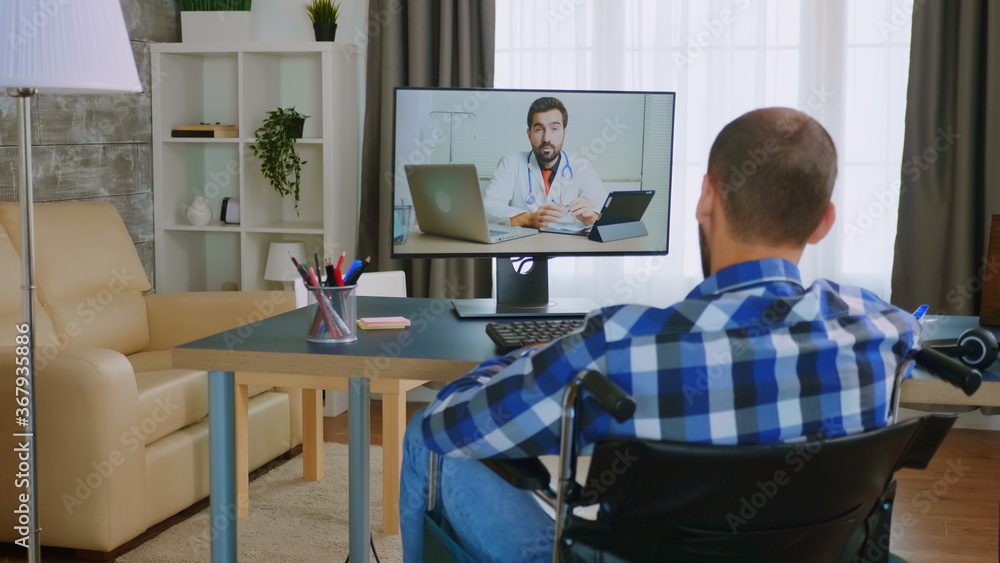Obraz premium Disabled young man in wheelchair during a video call with his doctor.