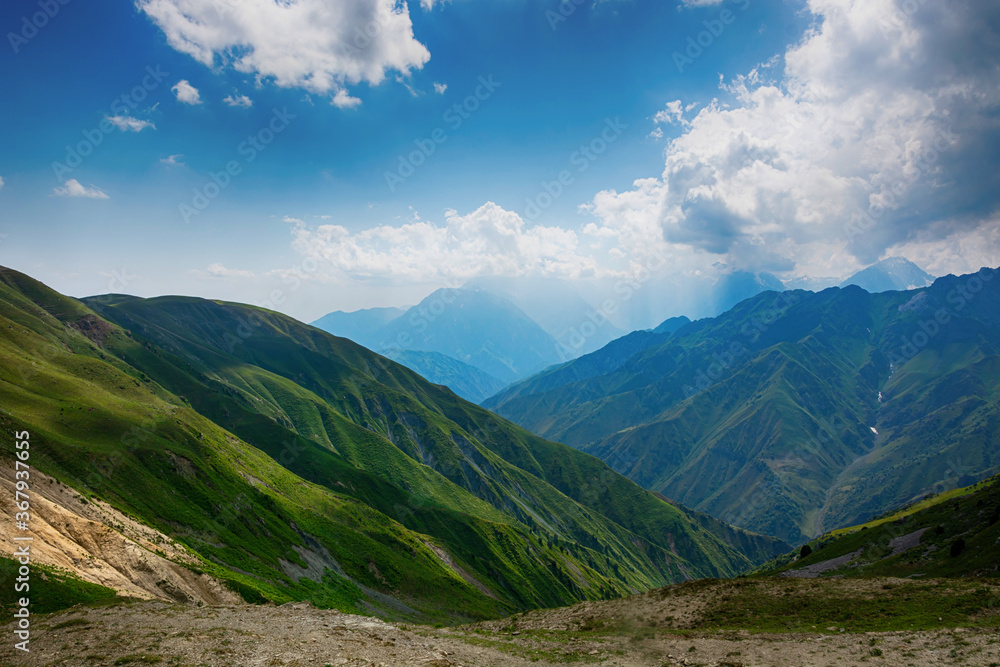 Fototapeta premium Idyllic summer landscape with hiking trail in the mountains with beautiful fresh green mountain pastures.