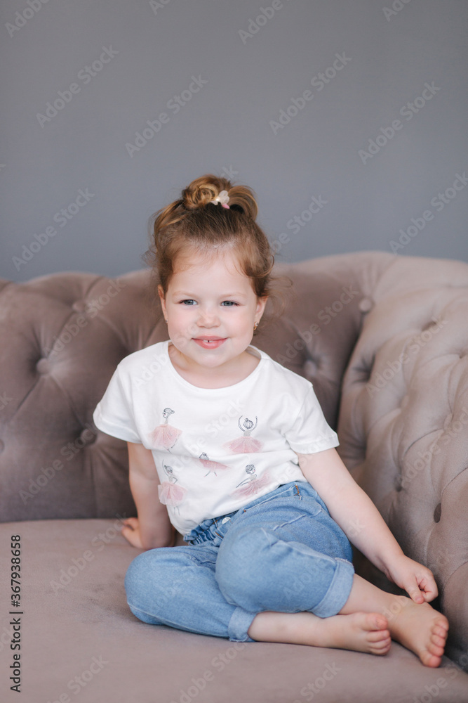 Portrait of beautiful little girl sits on sofa in studio Portrait of beautiful little girl sits on sofa in studio